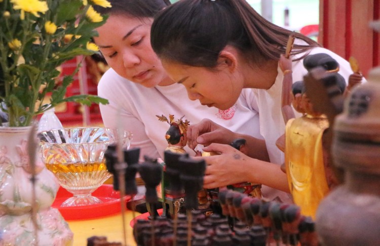 James’ sister, Joycelyn (left) cleaning the dust off the deity’s statue with another helper.